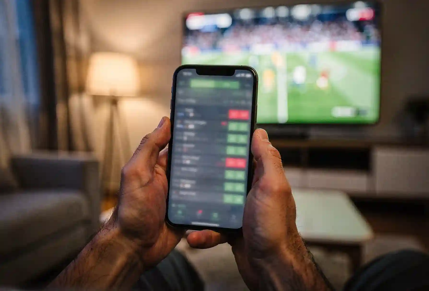 Live wedden op voetbal met smartphone en stadionscherm op de achtergrond